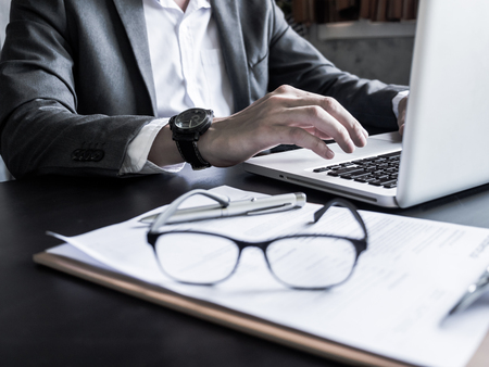 Close up of Businessman working on laptop with documents at the office.の写真素材