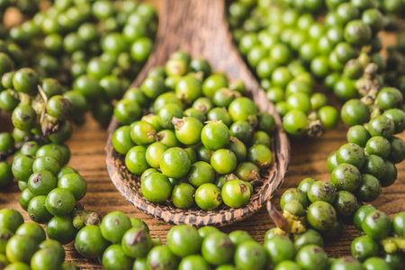 Green peppercorns on wooden background.