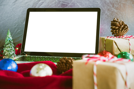 Laptop with white screen, gift boxes and christmas decoration on the table.の写真素材