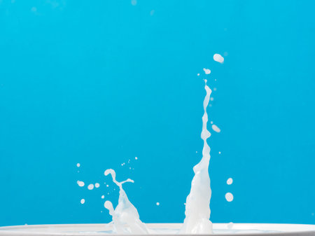 Splash of milk from a cup on blue background.の写真素材