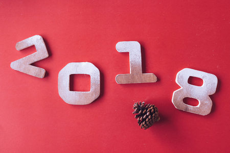 Wooden numbers 2018 with pine cone on red background. Happy New Year conceptの写真素材