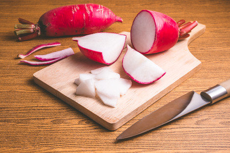 Fresh Pink Radishes on wooden cutting board over wooden table background.の写真素材