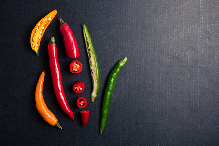 Colorful mix of chili pappers on black background. Free space for textの写真素材