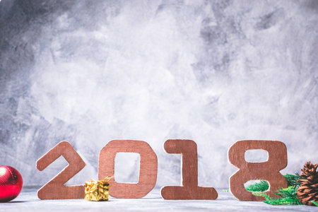 Wooden numbers 2018 with Christmas decoration on gray grunge background.