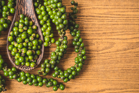 Green peppercorns on wooden background. Free space for textの写真素材