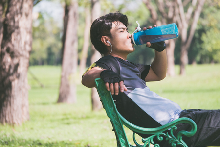 A man fresh up himself after exercise by drinking fresh water.の写真素材