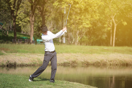 Asian man golf player swinging driver golf club on golf course.の写真素材
