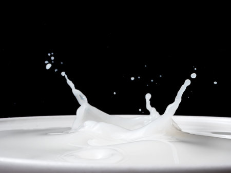 Splash of milk from a cup on black background.の写真素材