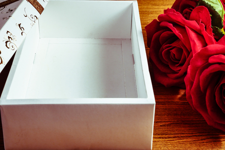 Empty white gift box with red roses on wooden background. Concept of Valentine Day.の写真素材