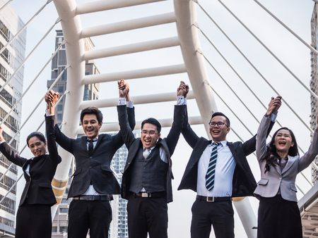 Successful Asian business team celebrating their triumph with arms up. Teamwork and success conceptの写真素材