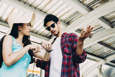 Asian woman is pointing at a wristwatch with argument feeling to boyfriendの写真素材