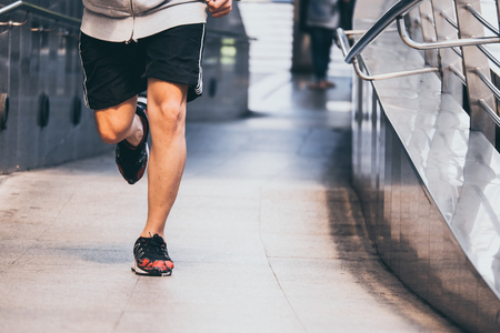 Close up of Young athletic man jogging on city bridge at the morning.の写真素材
