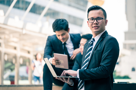 Group of  Asian business men working outdoor with computer devices. Technology and teamwork conceptの写真素材