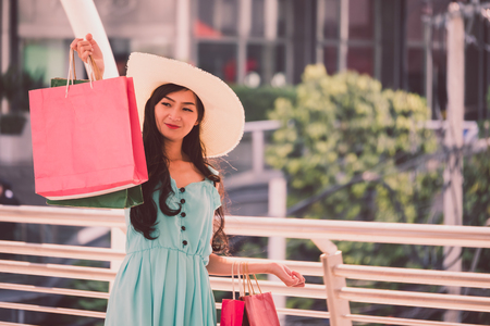 Happy young woman with shopping bags enjoying in shopping, Asian girl is having fun with her purchases in city. Consumerism and lifestyle conceptの写真素材