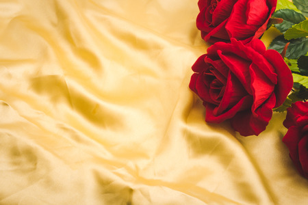 Bunch of Red roses on golden fabric background. Free space for textの写真素材