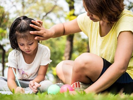 Close up of Mother teaching daughter for writing in a parkの写真素材