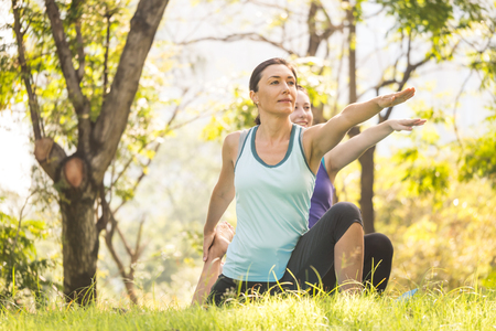 Group of women doing yoga exercises in the park. Concept of healthy lifestyle.の写真素材