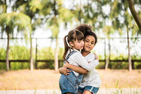 Cheerful little girls hugging in a park.の写真素材