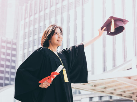 Graduation day, Asian woman with graduation cap and gown holding diploma, Successful conceptの写真素材