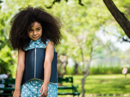 Beautiful girl holding a book, against green of summer park.の写真素材