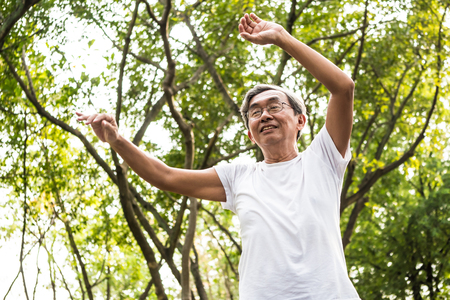 Senior asian man doing physical exercise in a park. Healthcare conceptの写真素材