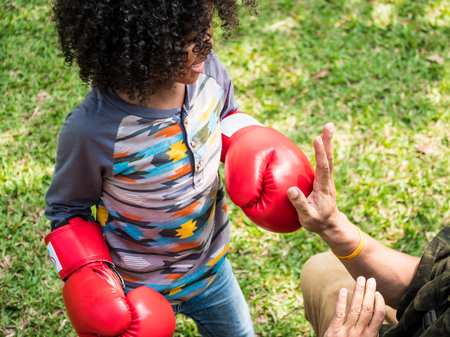 A little boy with red boxing gloves in a parkの写真素材