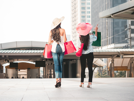 Back view of young women with shopping bags enjoying in shopping, Asian girls are having fun with their purchases in city. Consumerism and lifestyle conceptの写真素材