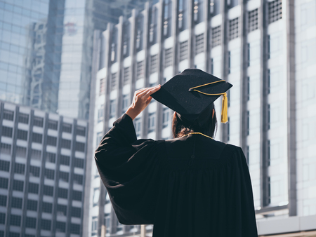 Graduation day, Back view of Asian woman with graduation cap and gown holding diploma, Successful conceptの写真素材