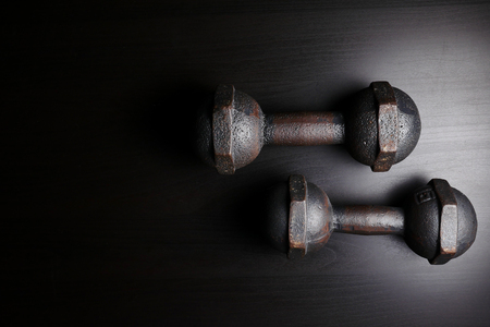 Old iron dumbballs on black wooden table background. copy spaceの写真素材