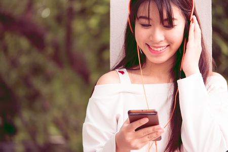 Young beautiful happy woman in headphones listening to music with her smartphoneの写真素材
