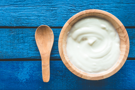 Top view of yogurt in wooden bowl on wooden tableの写真素材