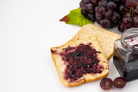 Whole wheat bread with grape jelly spread on a white background.の写真素材