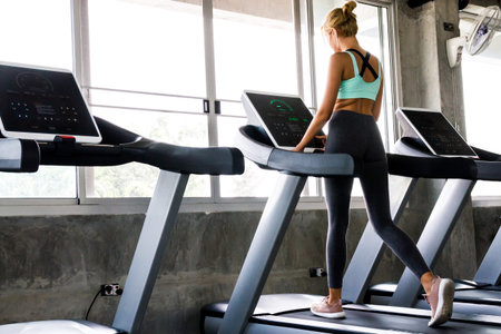 Young woman running on the treadmill at the gym
