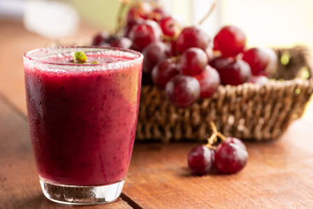 Glass of Grape juice smoothie on wooden tableの写真素材