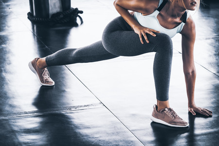 Attractive young woman stretching and warming up before workout at the gymの写真素材