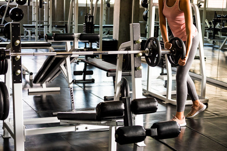 Young woman preparing for training by using barbell at the gym.の写真素材