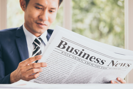 Asian Businessman is sitting and reading news from a newspaper at the office.の写真素材