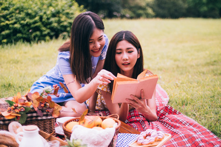 Two female friends enjoying picnic together in a park.の写真素材