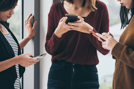 People are focusing on smartphones while standing togetherの写真素材