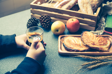 Male hands holding a cup of coffee. Snacks and fruits on a table.の写真素材
