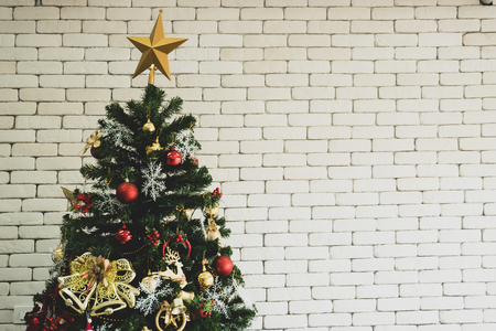 Close up of decorated Christmas tree with white brick wall.の写真素材