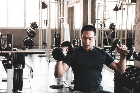 Young man exercising building muscles at the gymの写真素材