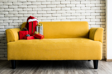 Gift boxed on yellow sofa with white brick wall.の写真素材