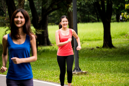 Portrait of young girl jogging in a park with her friendの写真素材