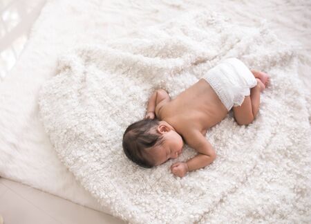 Sweet newborn baby sleeping on white bedの写真素材