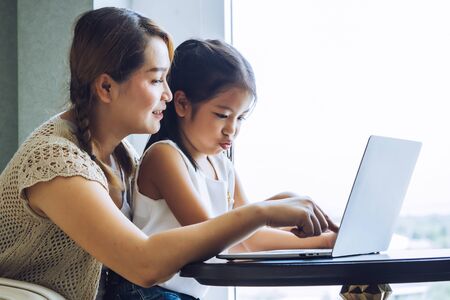 Happy mother with little kid daughter using laptop at homeの写真素材