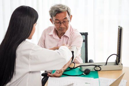 Doctor measuring blood pressure of elderly man in medical office