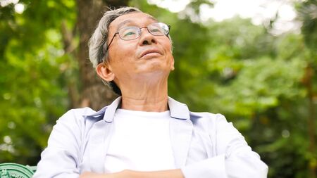 Happy asian man sitting on a bench at the park.の写真素材