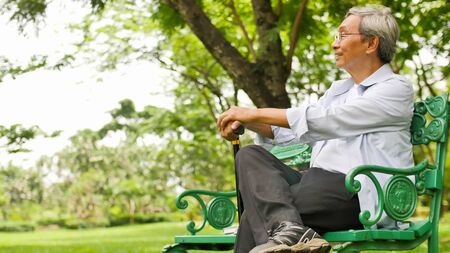 Happy asian man sitting on a bench at the park.の写真素材
