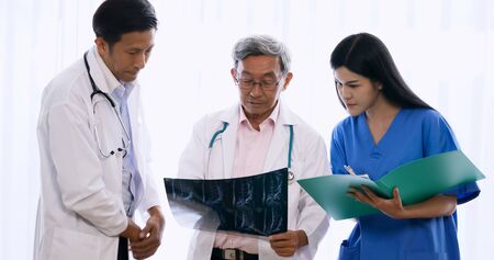 Doctor and medical assistants discussing about diagnosis result on x-ray film.の写真素材